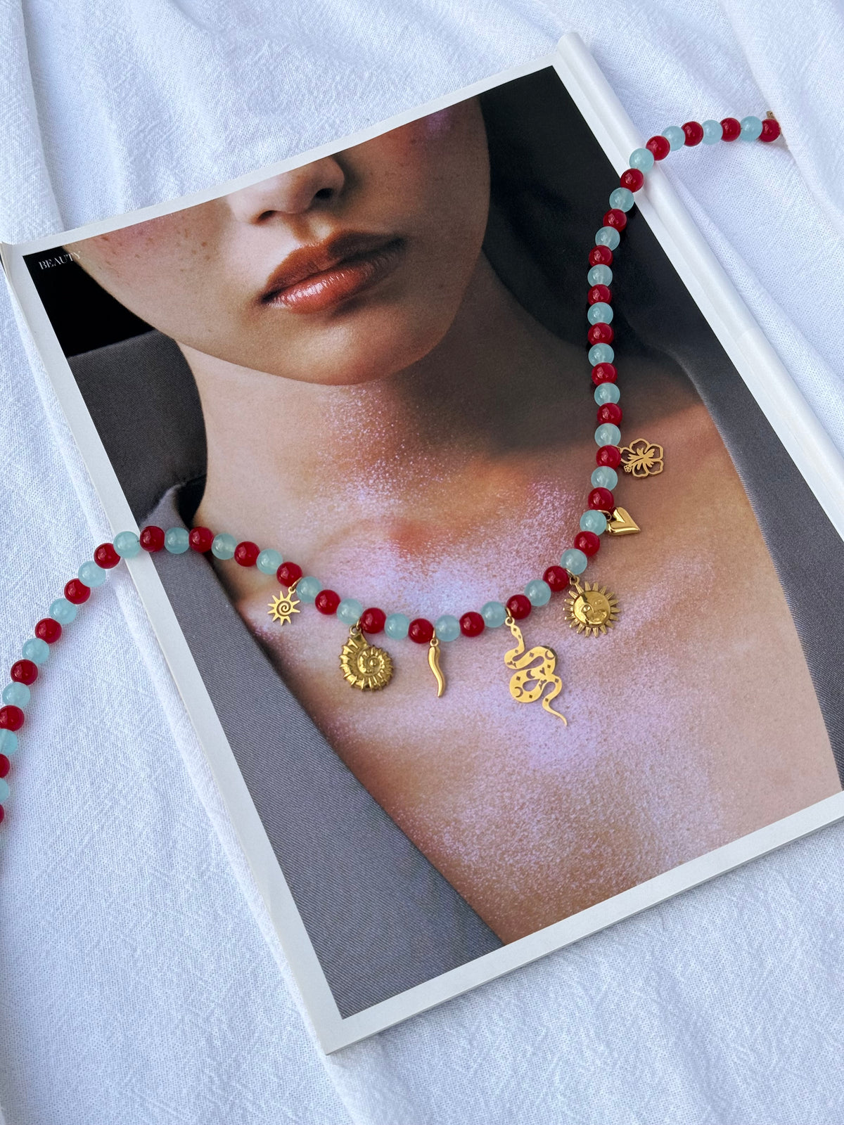 Gold Charmed Necklace — red and blue glass beads with scattered gold sun, shell, cornicello, snake, heart and hibiscus charms, 49cm, handmade by Salty Gypsy