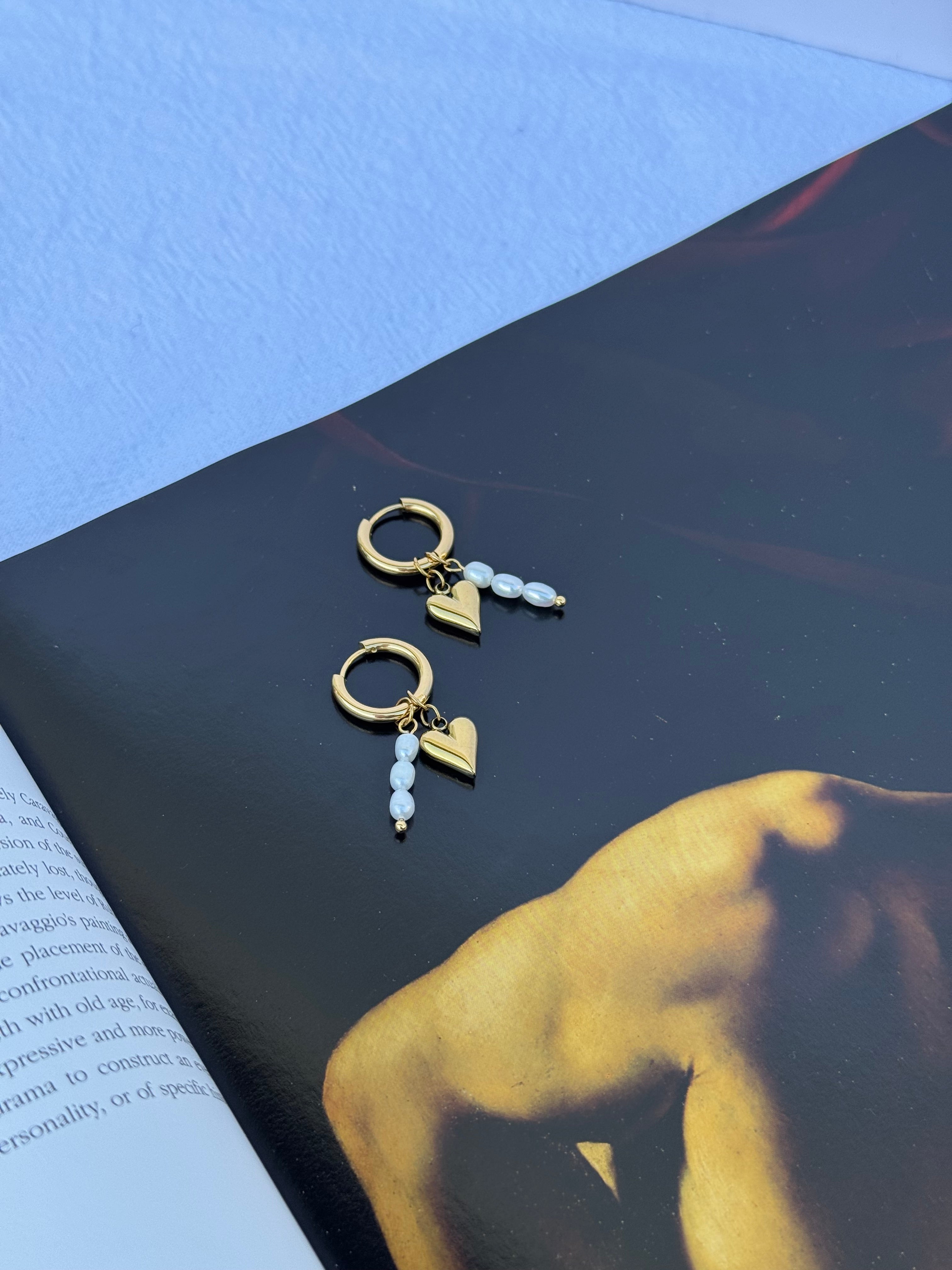 Juliet Hoops in gold and pearl — slim 18K gold huggie earrings with a dainty heart charm and removable rice pearl stack, handmade by Salty Gypsy